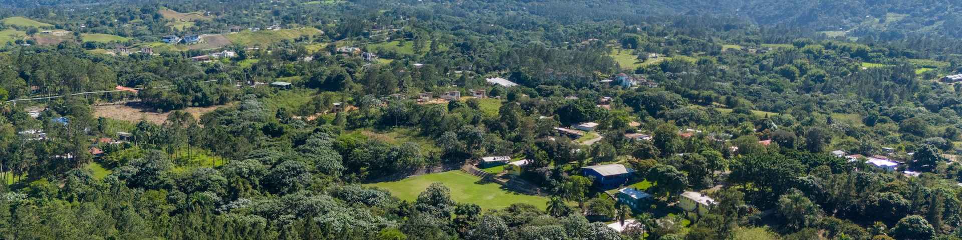 A lush green valley with scattered houses and a mountain range in the background.