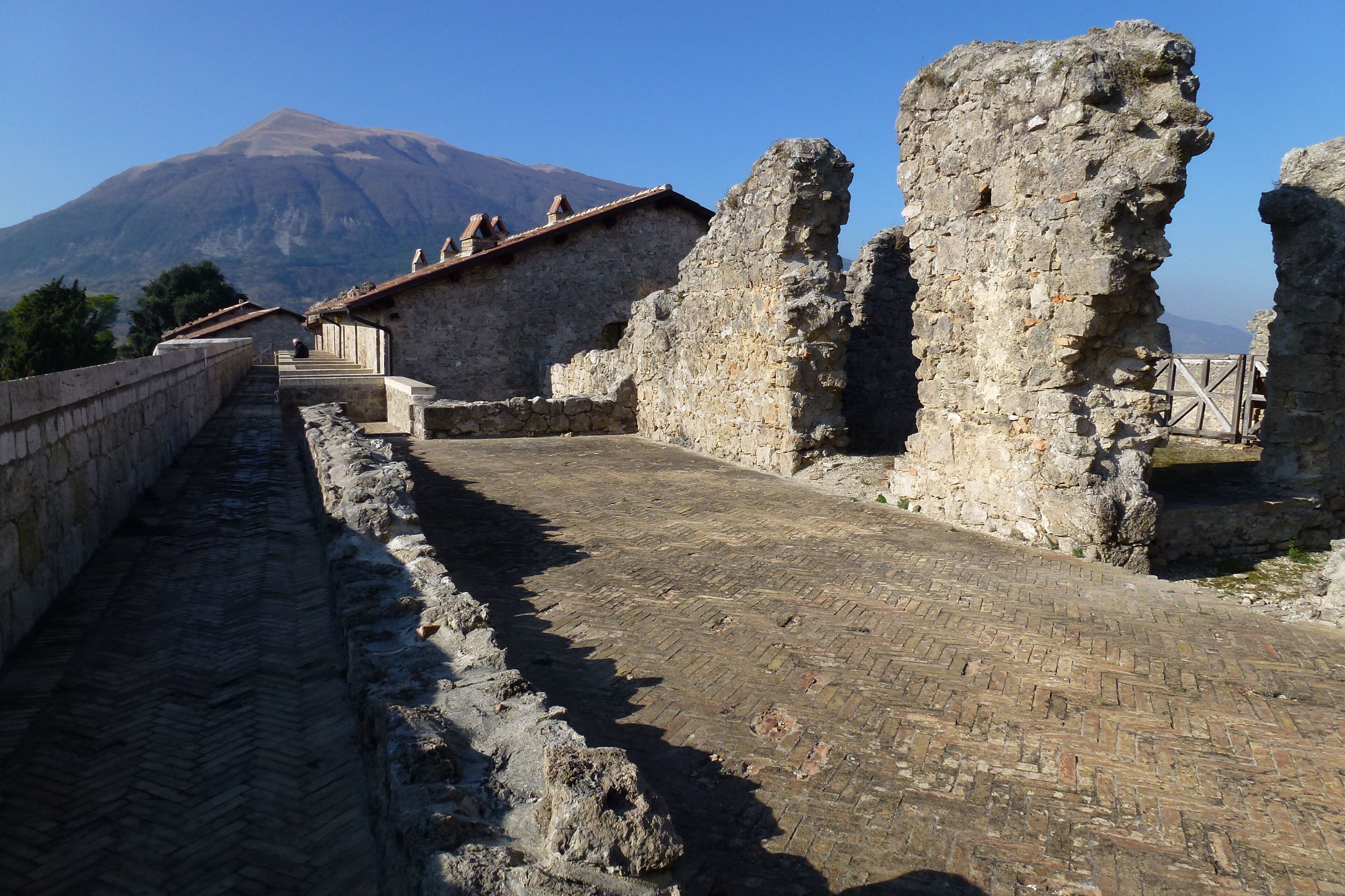 Antiche rovine in pietra con una montagna sullo sfondo.