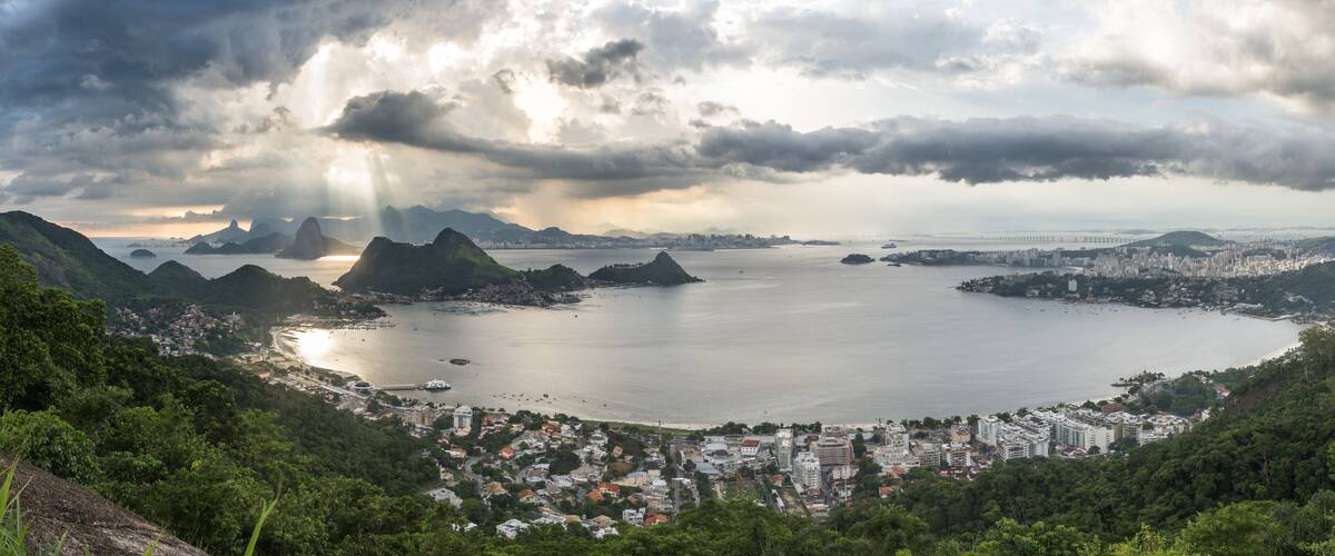 Wide Horizontal Panorama showing São Francisco Beach and Charitas in Niterói and Rio de Janeiro City Mountains During a Magical Sunset with Beautiful Light Rays