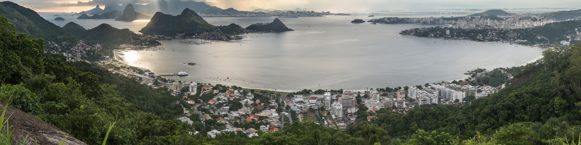 Wide Horizontal Panorama showing São Francisco Beach and Charitas in Niterói and Rio de Janeiro City Mountains During a Magical Sunset with Beautiful Light Rays