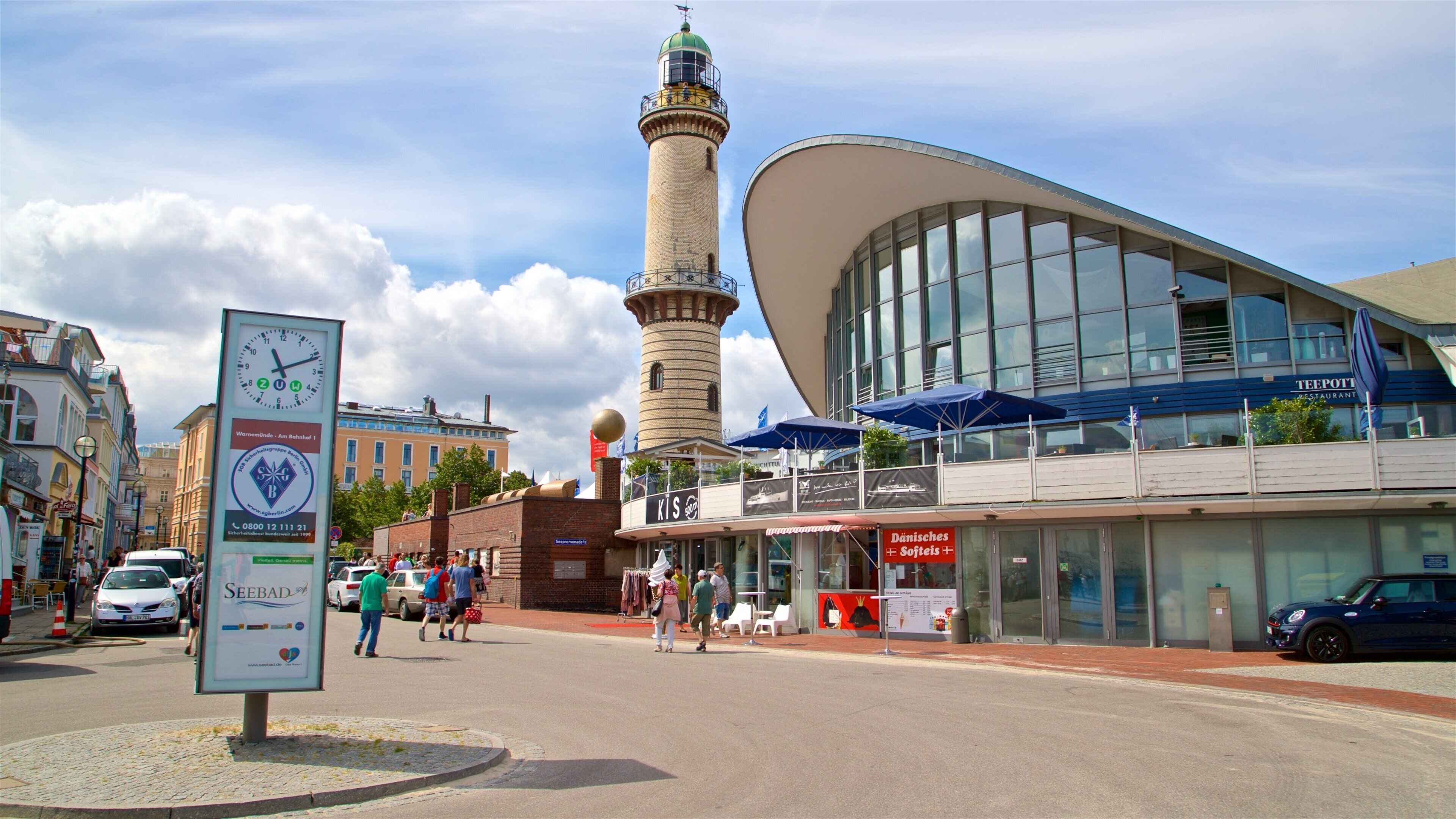 A modern building with a curved facade, a tall tower, and a signboard with a clock.