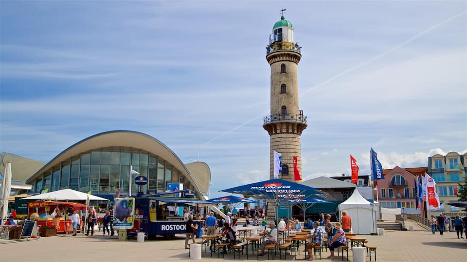 A bustling outdoor market with food stalls, a prominent tower, and a modern building.