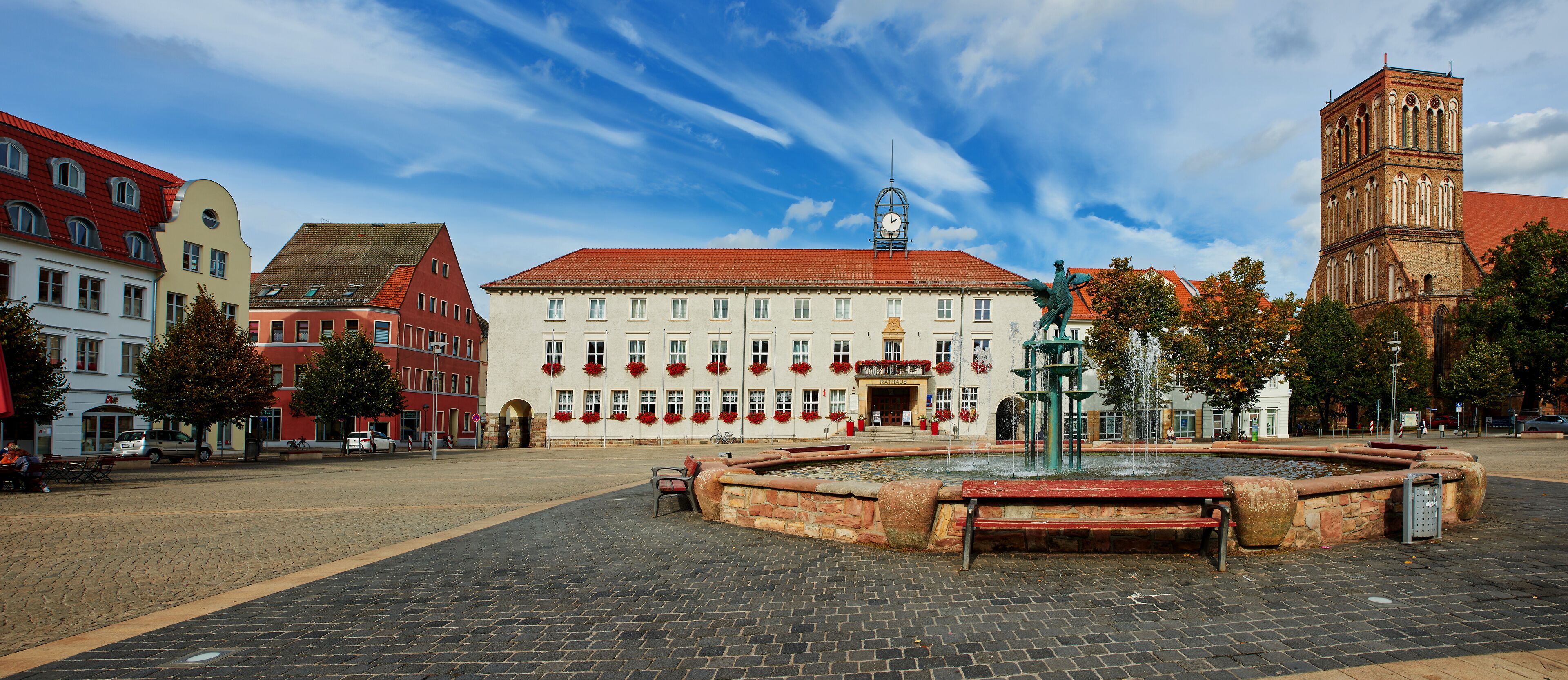 A historic square with a fountain, a church, and colorful buildings.