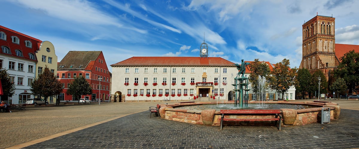 A historic square with a fountain, a church, and colorful buildings.