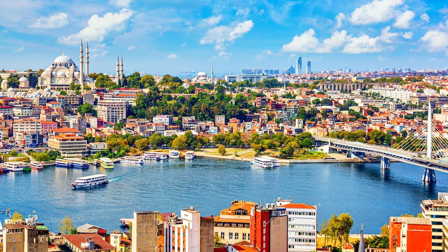 Touristic sightseeing ships in Golden Horn bay of Istanbul and mosque with Sultanahmet district against blue sky and clouds. Istanbul, Turkey during sunny summer day.