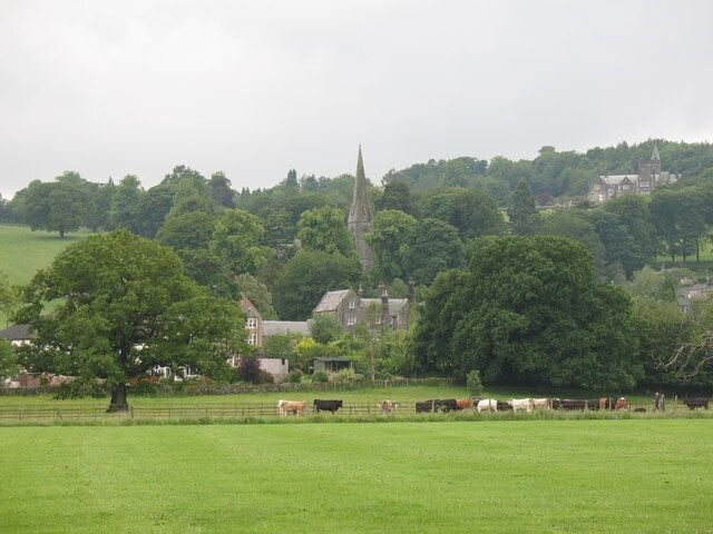 View across playing fields at Birstwith The goalposts have been taken down for the summer, so there is a clear view of grazing cattle and the village church on the hill.