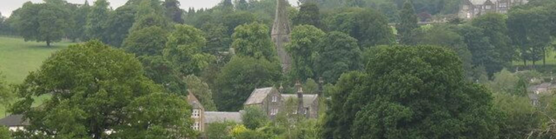 View across playing fields at Birstwith The goalposts have been taken down for the summer, so there is a clear view of grazing cattle and the village church on the hill.
