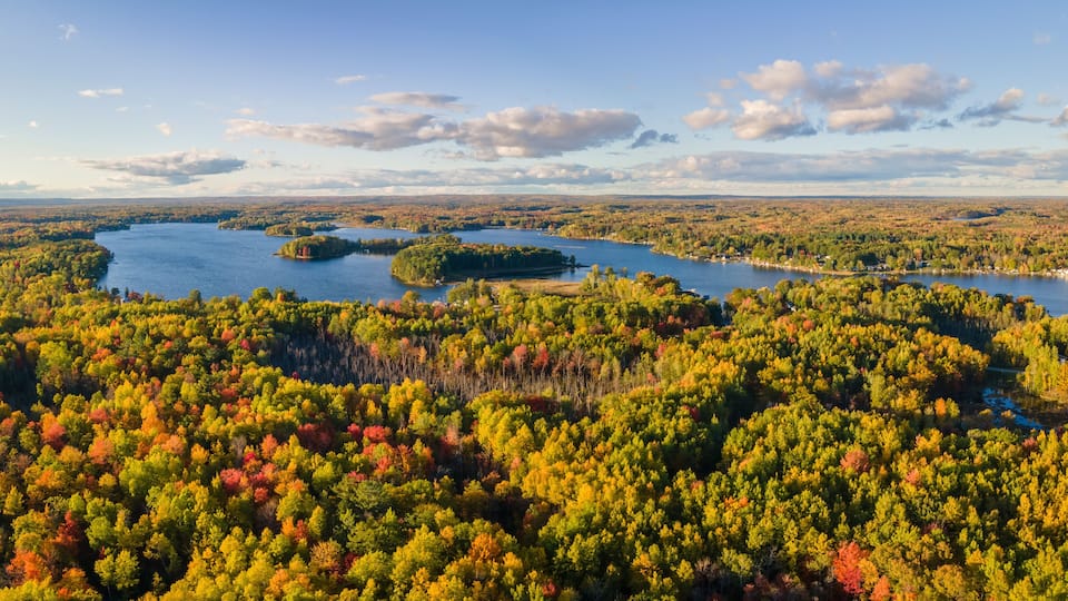 A lake surrounded by dense forest with autumn foliage.