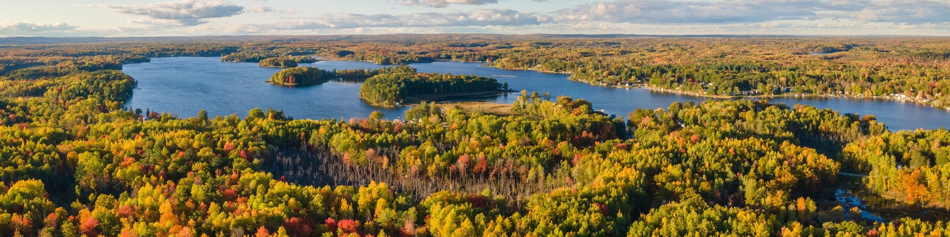 Un lago rodeado de un bosque denso con follaje otoñal.