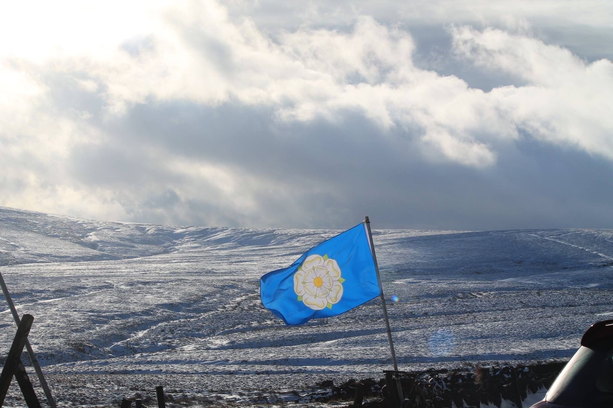 A snowy landscape with a flag featuring a blue background and a white flower.