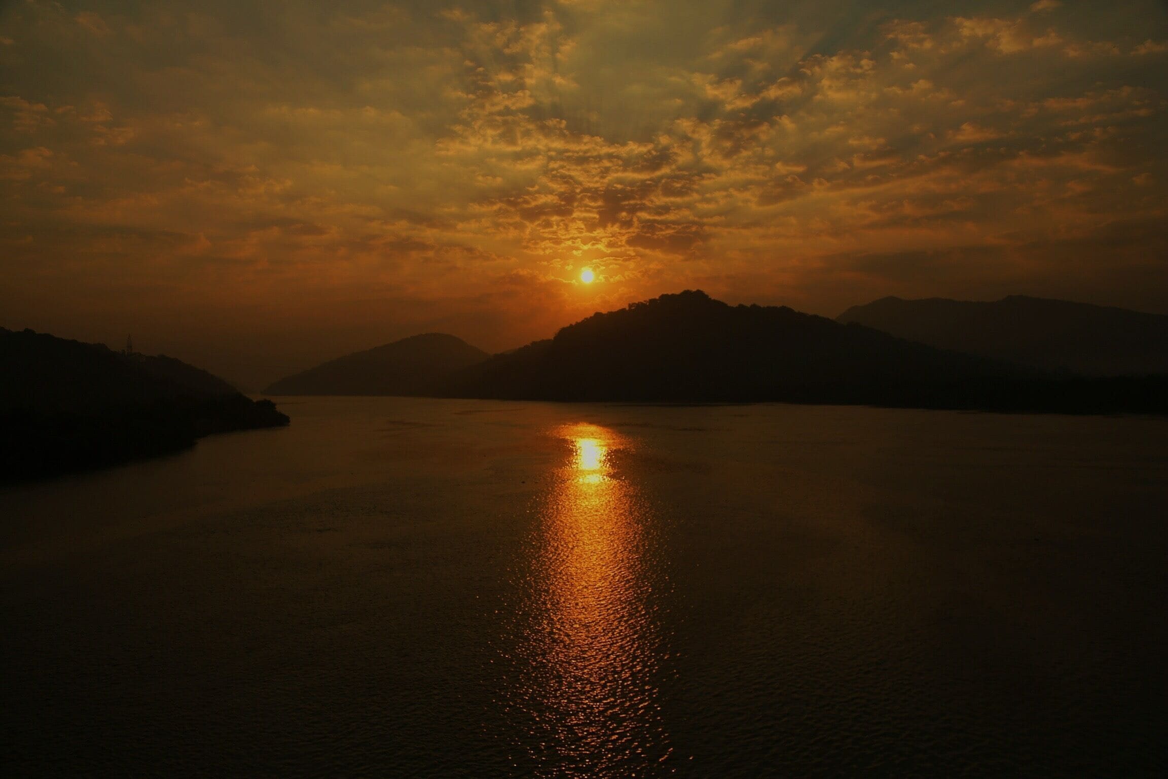 A sunset over a calm body of water with mountains in the background.