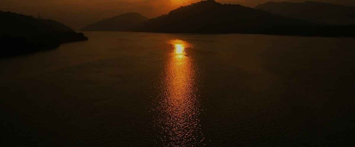 A sunset over a calm body of water with mountains in the background.