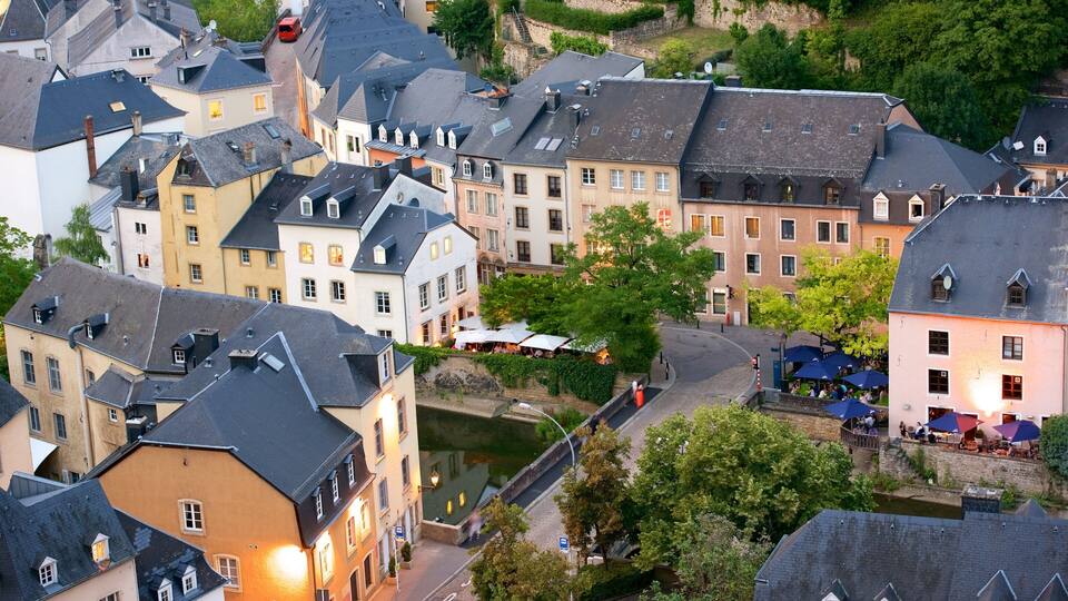 A European town with historic buildings, a canal, and outdoor seating at a café.