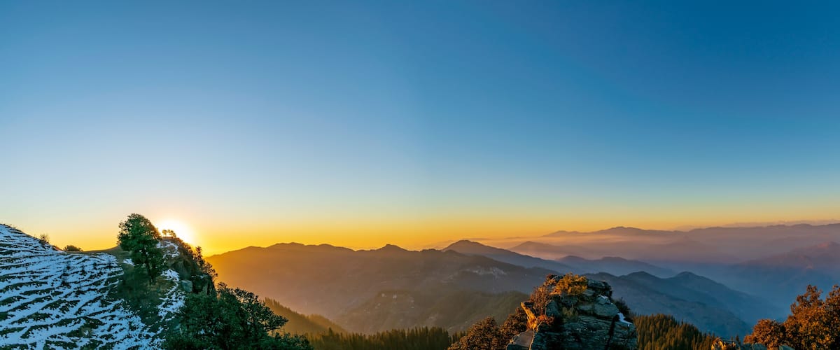 A mountainous landscape with a clear sky at sunrise or sunset.