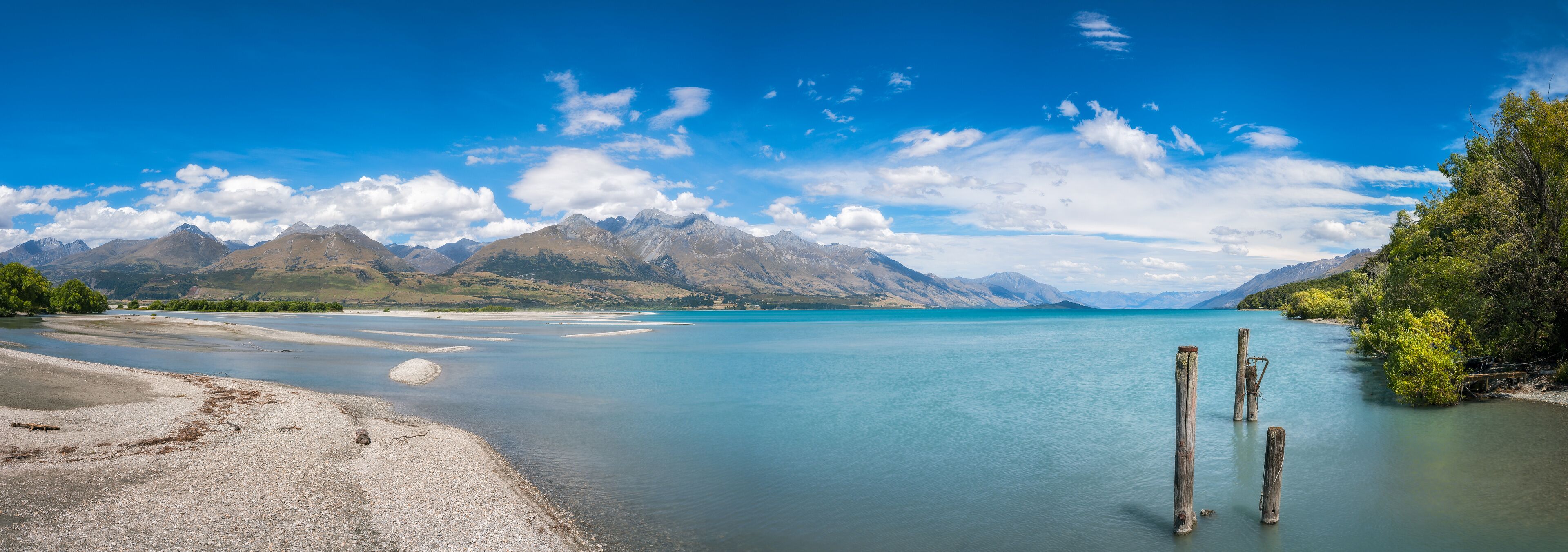 A calm lake with clear blue water, surrounded by mountains and a clear sky.