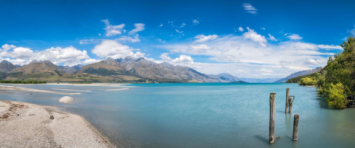 A calm lake with clear blue water, surrounded by mountains and a clear sky.