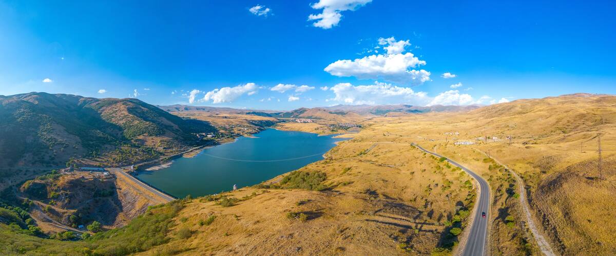 A valley with a lake, mountains, and a winding road.
