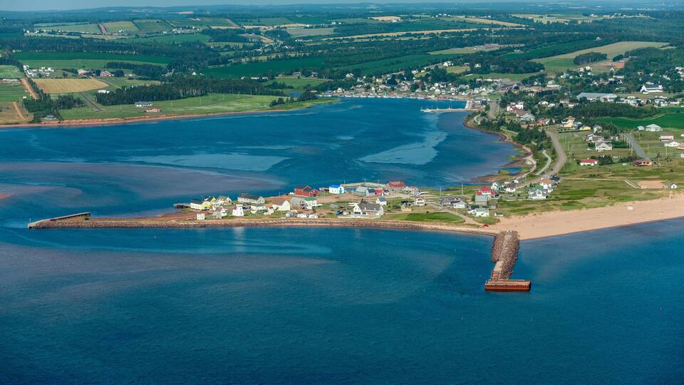 An aerial view of a coastal town with a pier extending into a large body of water.