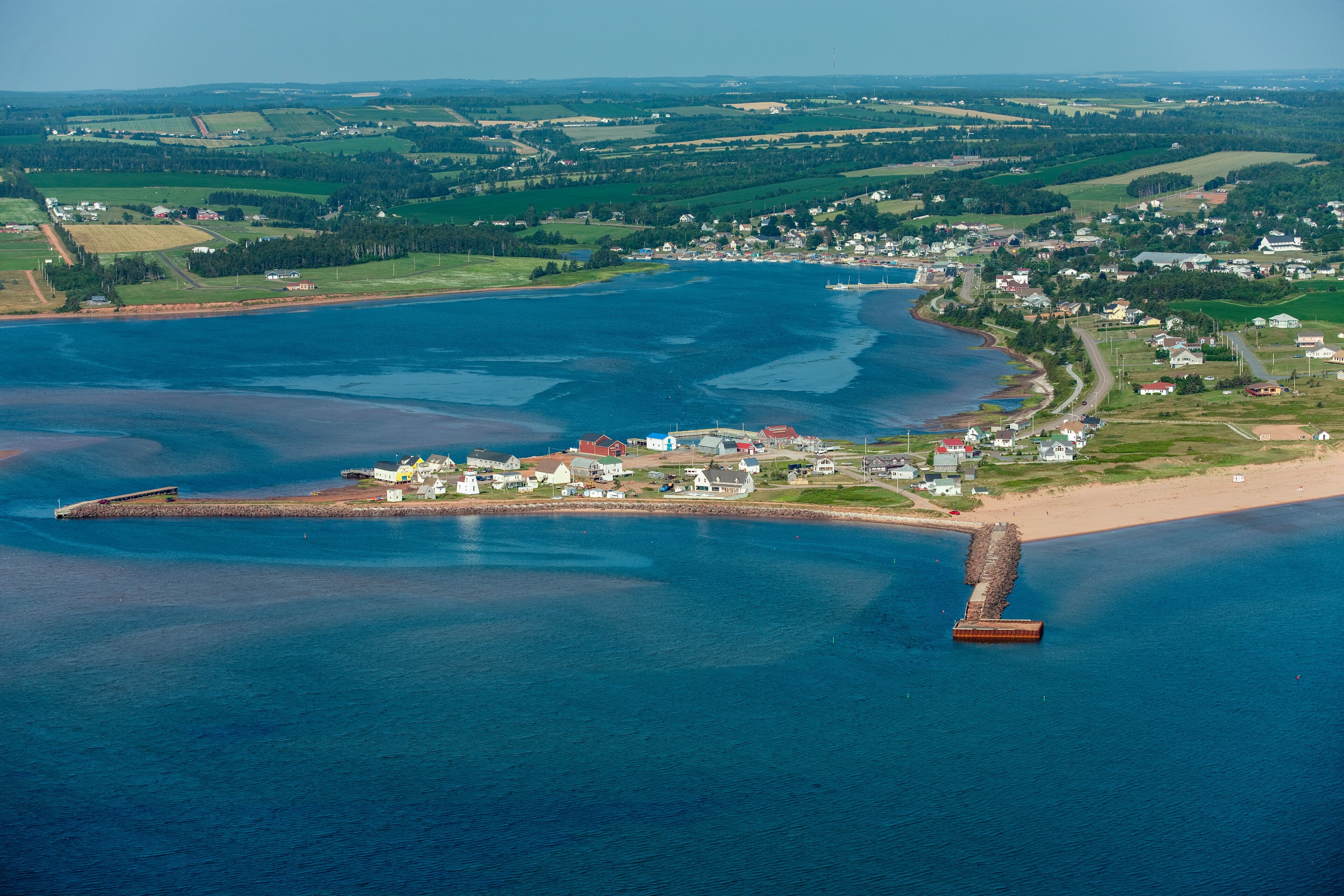 An aerial view of a coastal town with a pier extending into a large body of water.
