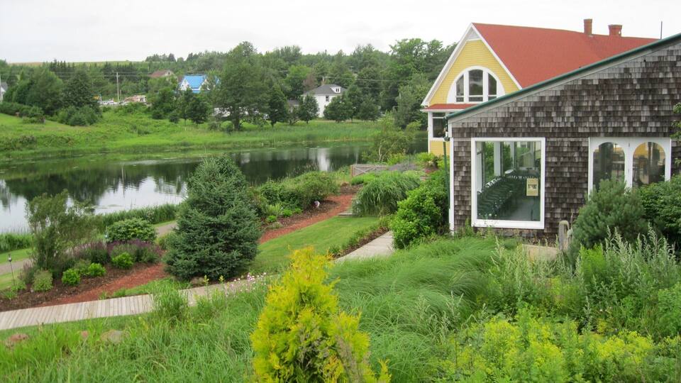 A house with a red roof and a pond in the foreground.