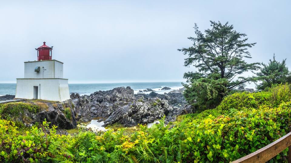 A lighthouse on rocky terrain with a view of the ocean.