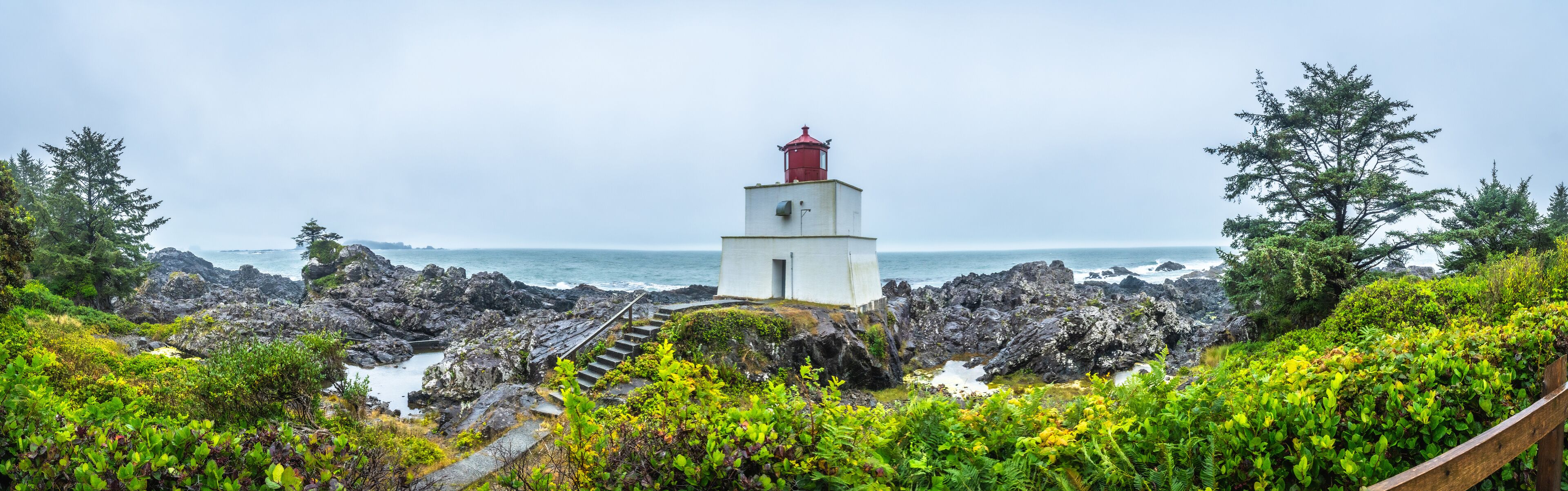 A lighthouse on rocky terrain with a view of the ocean.