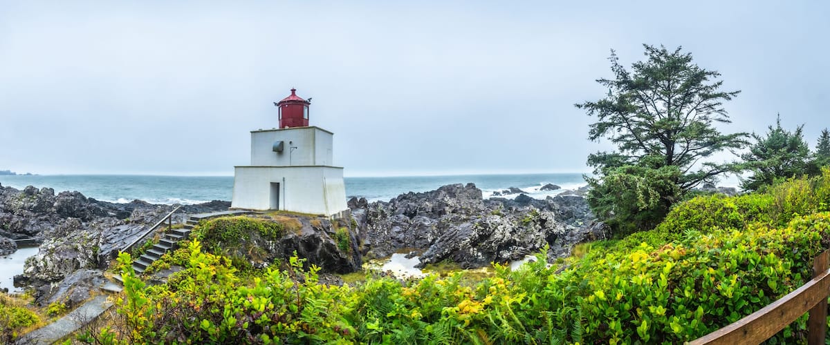 A lighthouse on rocky terrain with a view of the ocean.