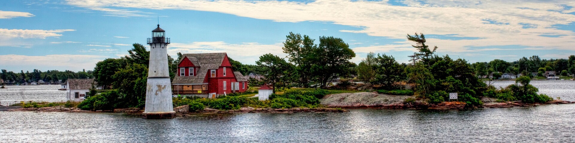 Un faro y una casa roja en una pequeña isla rodeada de agua.
