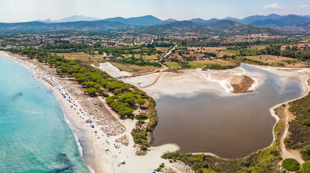 Paisagem costeira com uma praia, um lago e montanhas ao fundo.