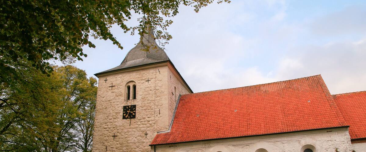 A church with a stone tower and a red-tiled roof.