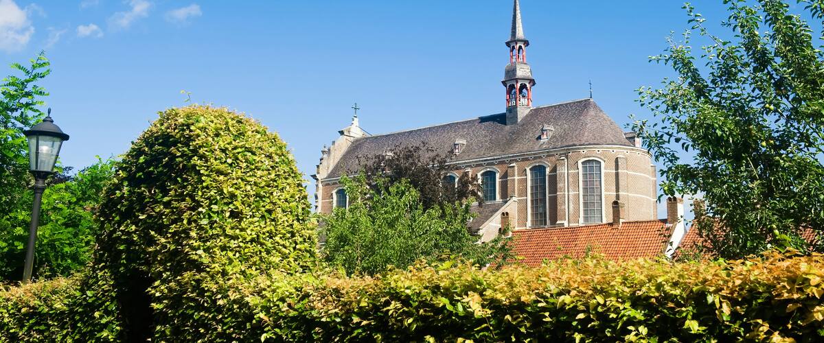 A church with a tall steeple and a red-tiled roof.