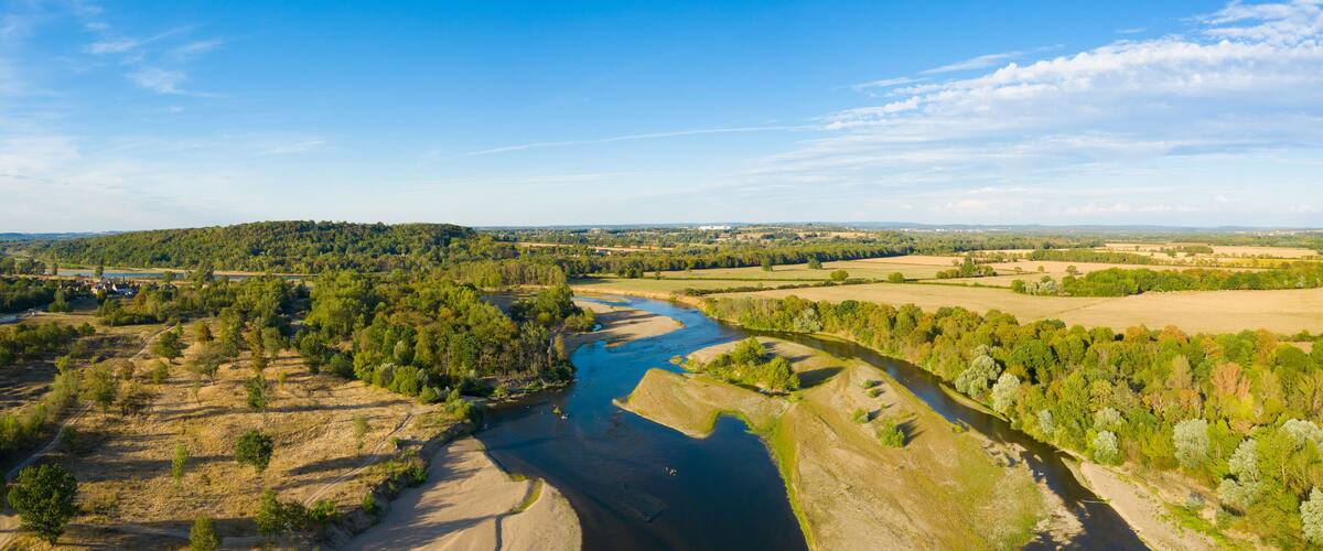 A river winding through a valley with surrounding fields and distant hills.