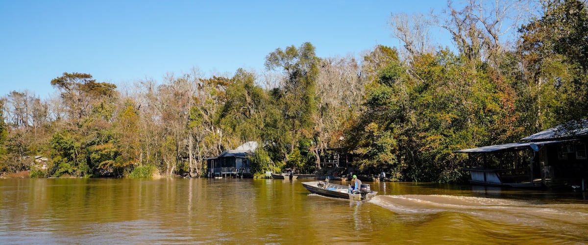 A cajun fisherman in a small boat makes his way down the Pearl River in Louisiana near a cajun fishing camp.