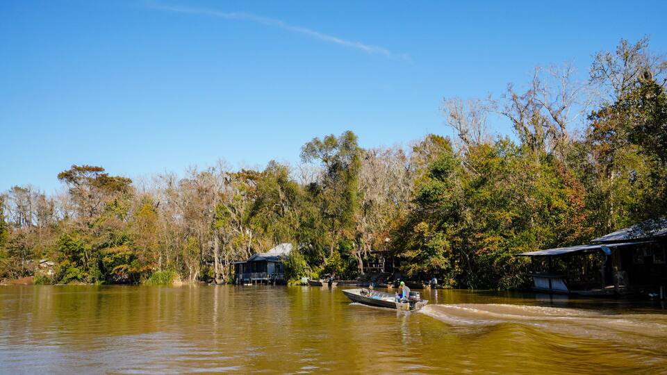A cajun fisherman in a small boat makes his way down the Pearl River in Louisiana near a cajun fishing camp.