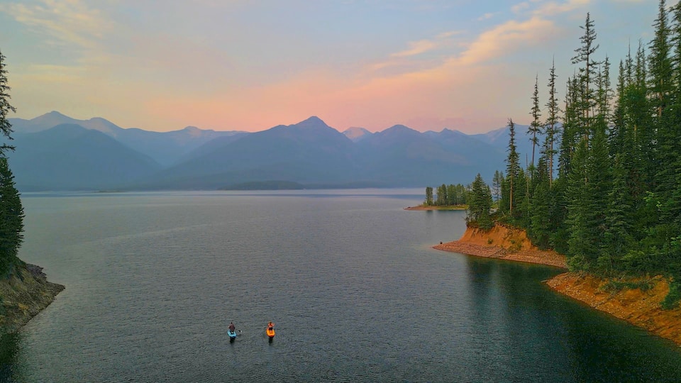 A calm lake surrounded by mountains and dense forest.