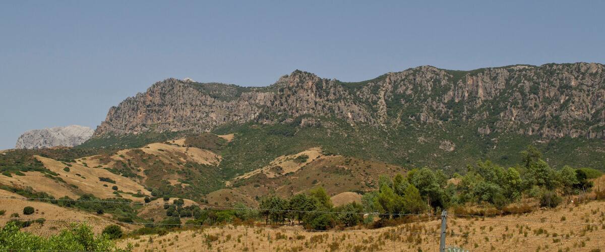 A mountainous landscape with a prominent rocky peak and sparse vegetation.