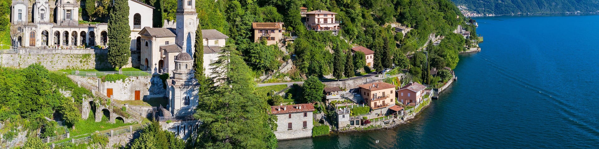 A coastal town with a prominent church, residential buildings, and a mountainous backdrop.