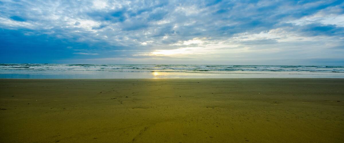 A beach with a wide sandy shore and a cloudy sky.