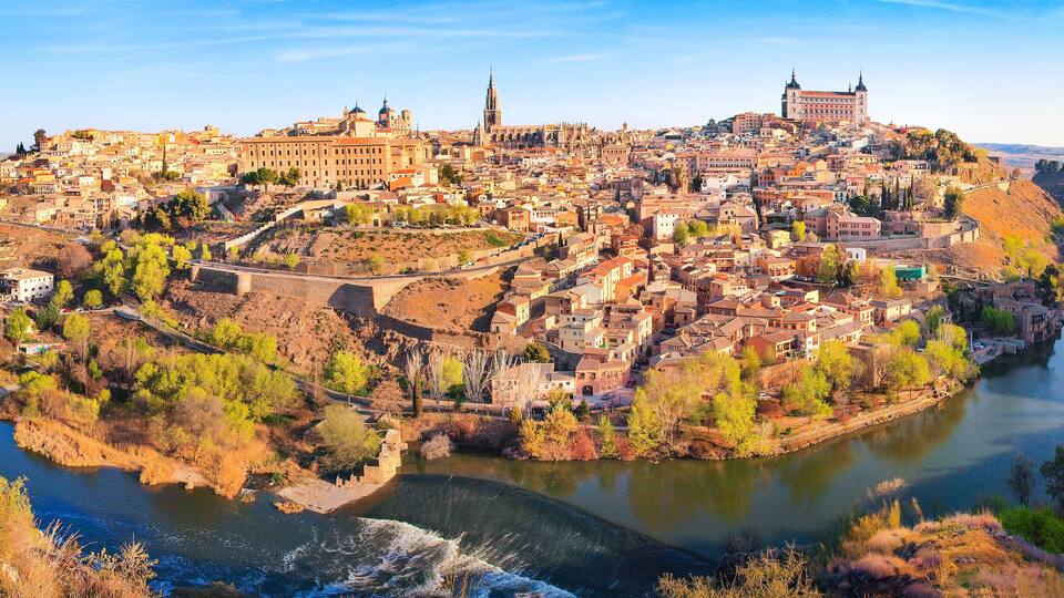 A panoramic view of a historic city with a river, including prominent buildings and a castle.