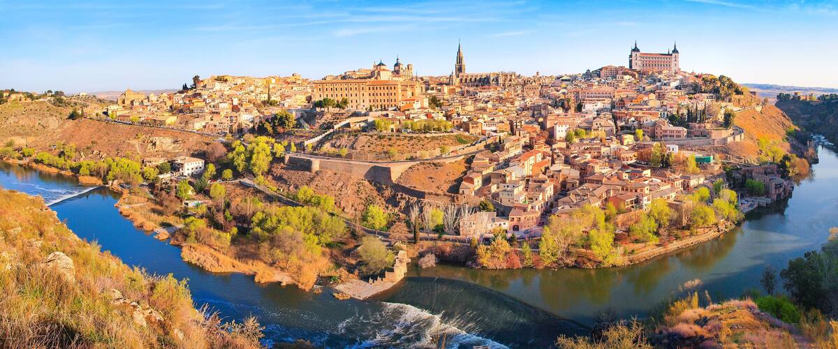 A panoramic view of a historic city with a river, including prominent buildings and a castle.