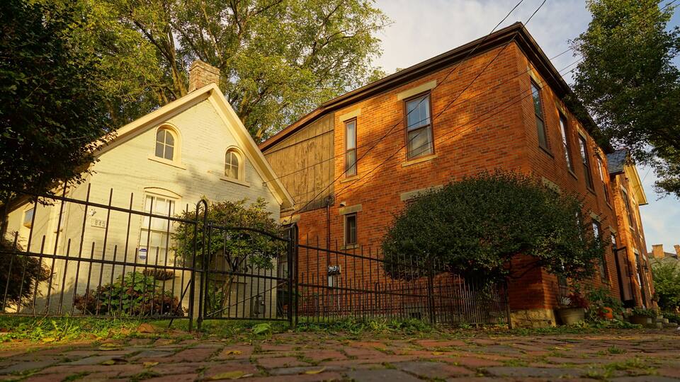 A historic brick building with a white facade and a black iron fence.