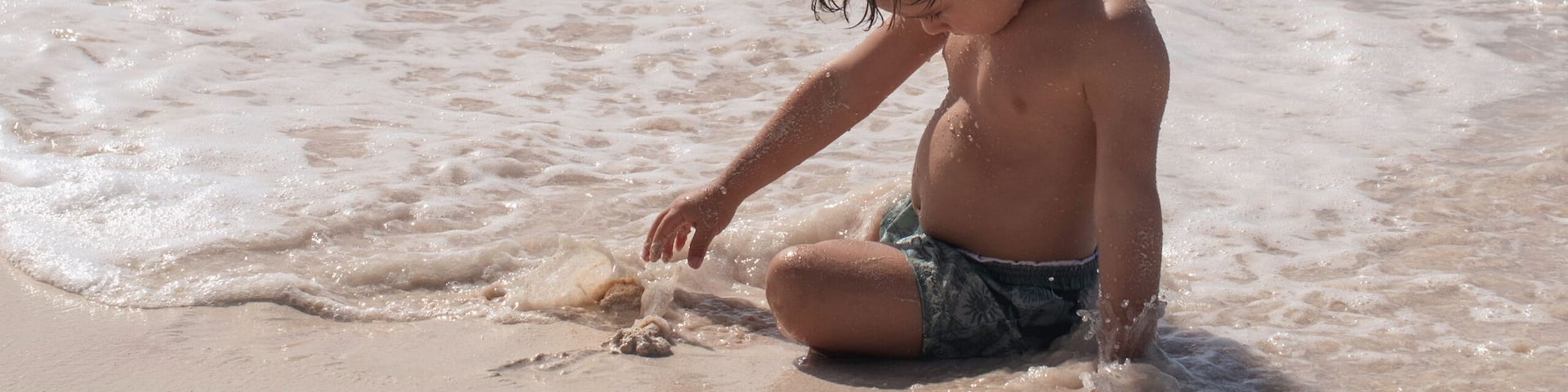 Young boy playing in sand on beach in caribbean