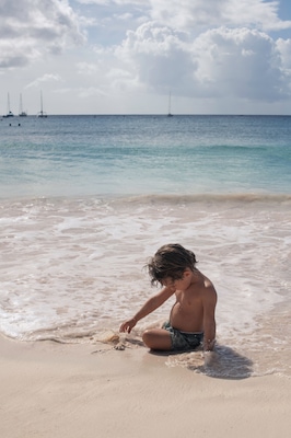 Young boy playing in sand on beach in caribbean