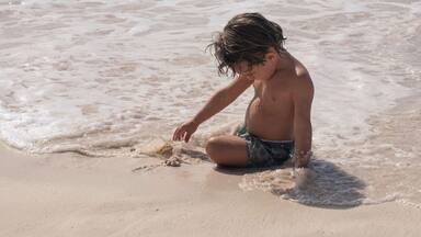 Young boy playing in sand on beach in caribbean