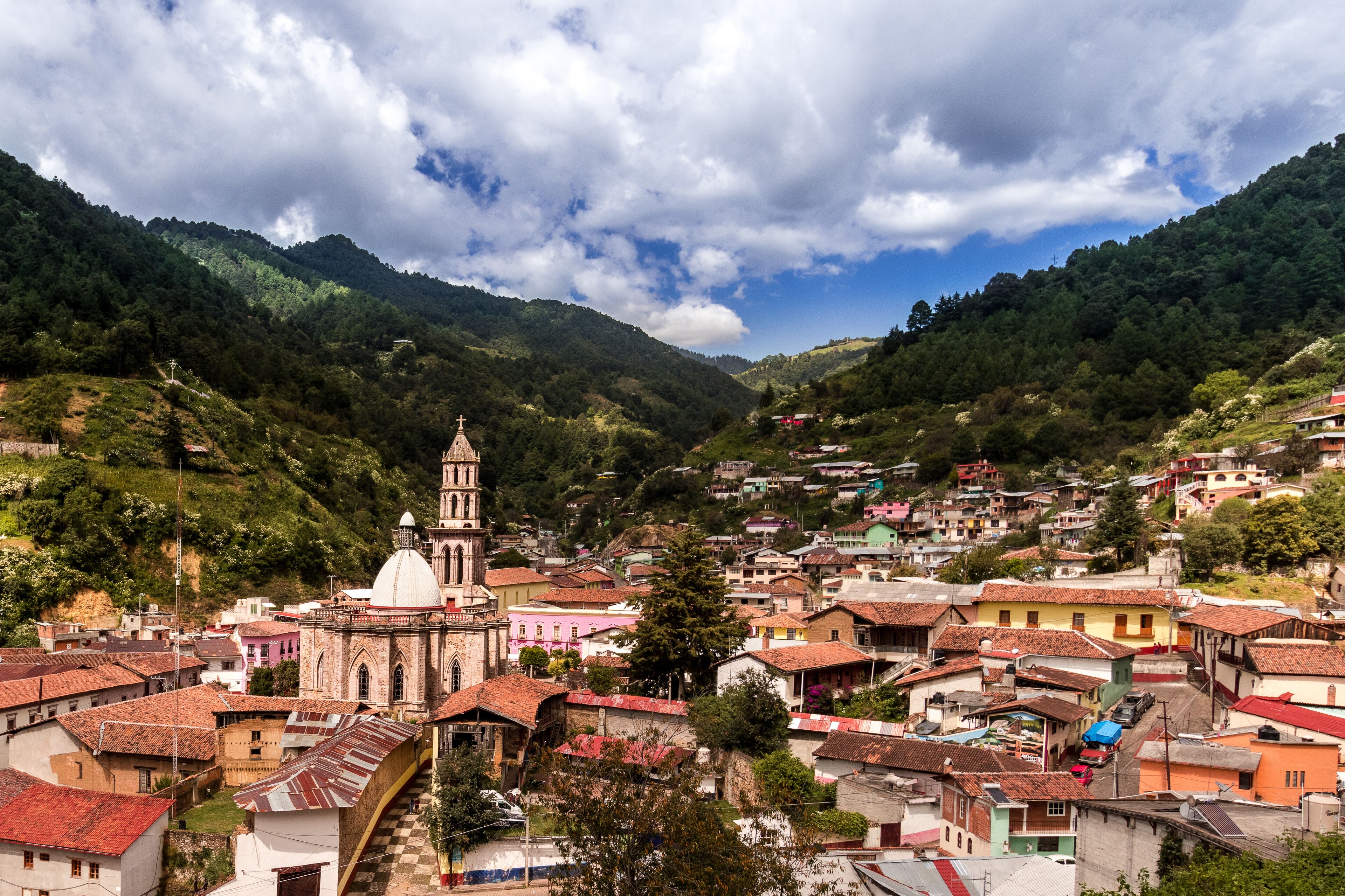 A town nestled in a valley with a prominent church and surrounding hills.