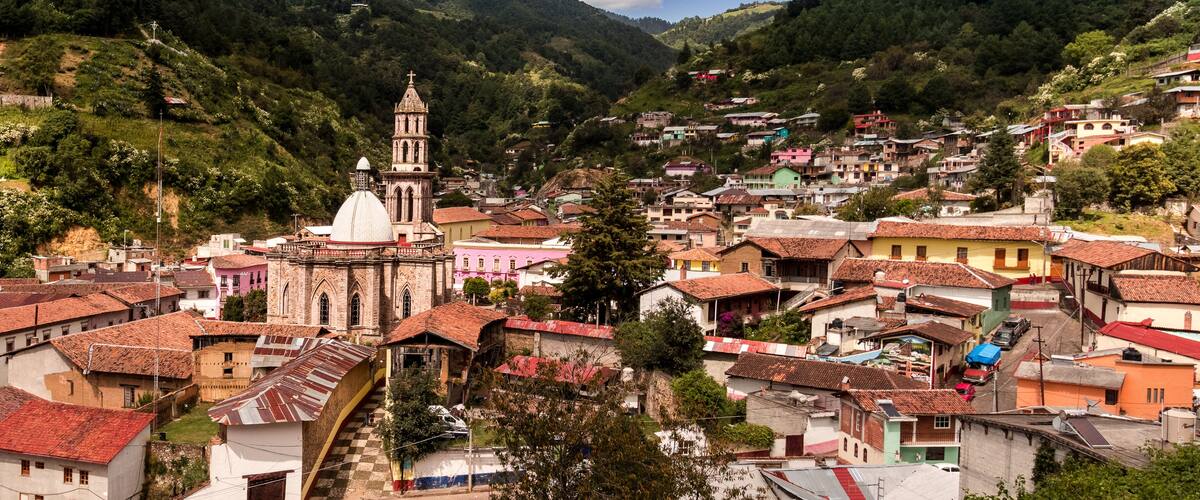 A town nestled in a valley with a prominent church and surrounding hills.