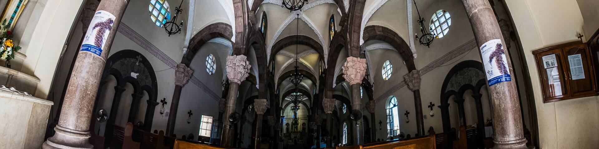 L’intérieur d’une église, avec de hauts plafonds en voûte, des fenêtres en arc de cercle et des colonnes richement décorées.