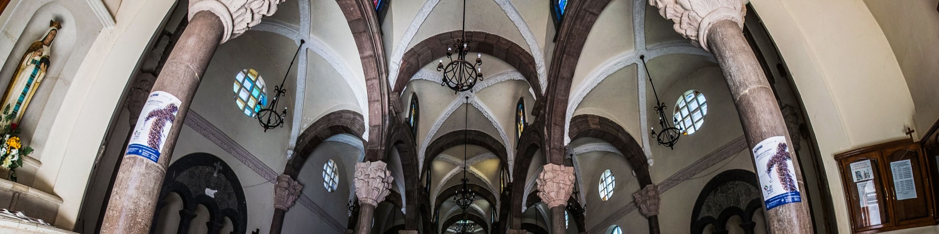 A church interior with high vaulted ceilings, arched windows, and ornate columns.