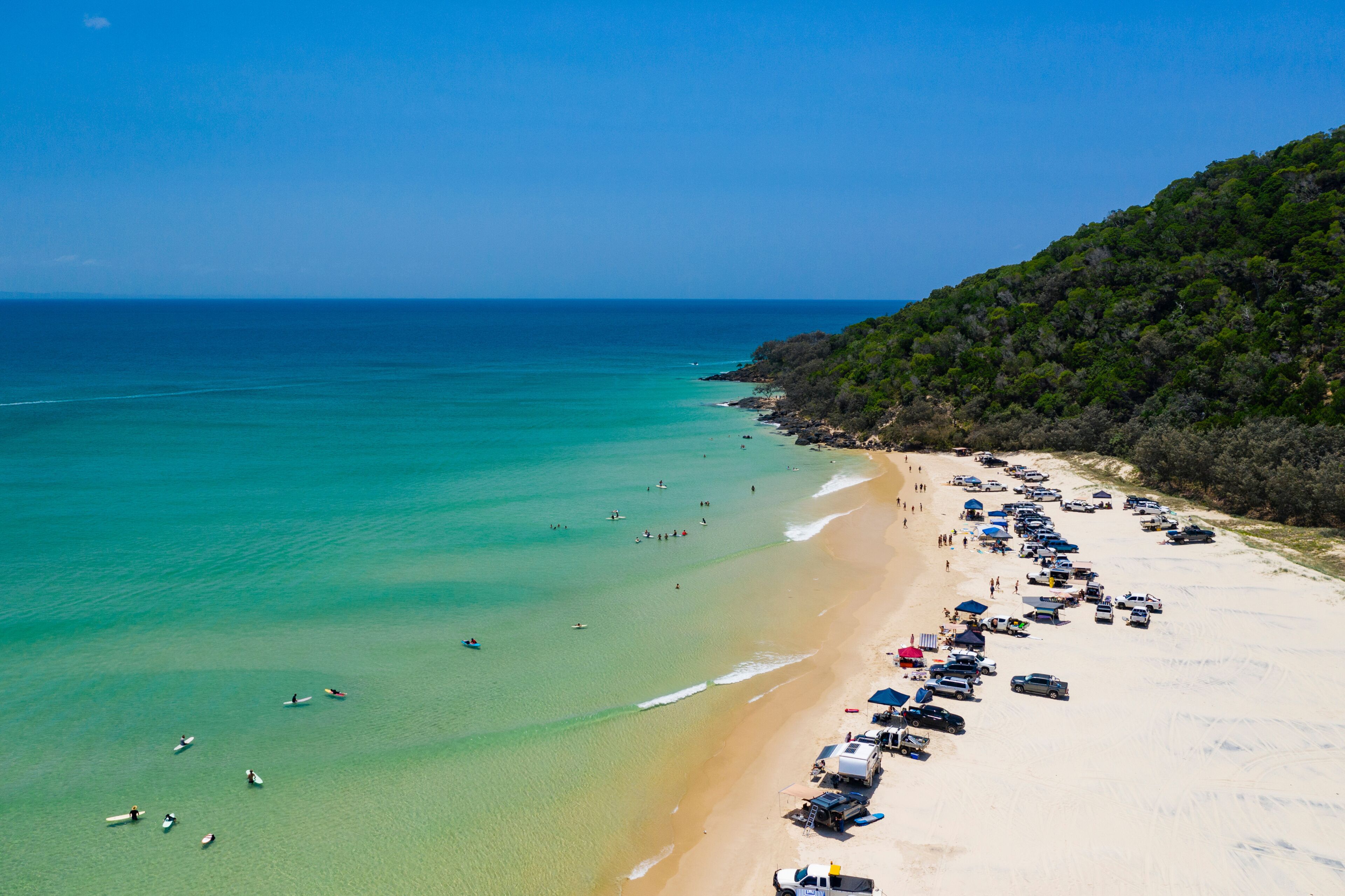4WD vehicles and surfers at Double Island Point on a sunny day