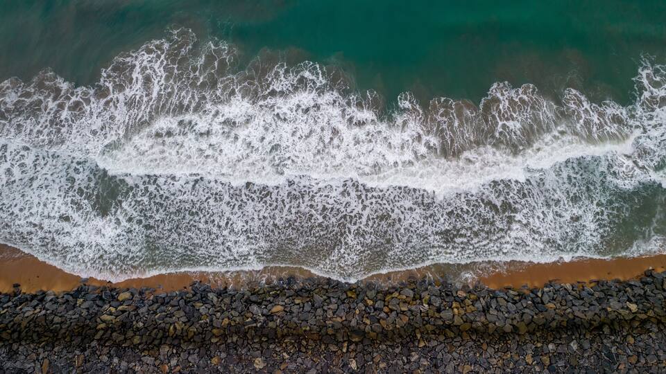 A rocky shoreline with waves crashing onto the beach.
